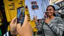 Seorang wanita berfoto dengan kaus bergambar Capres Brasil, Jair Bolsonaro dari sayap kanan di sebuah toko pinggir jalan yang populer di Sao Paulo, 8 Oktober 2018. Bolsonaro unggul dalam penghitungan suara pemilu putaran pertama. (AFP/NELSON ALMEIDA)