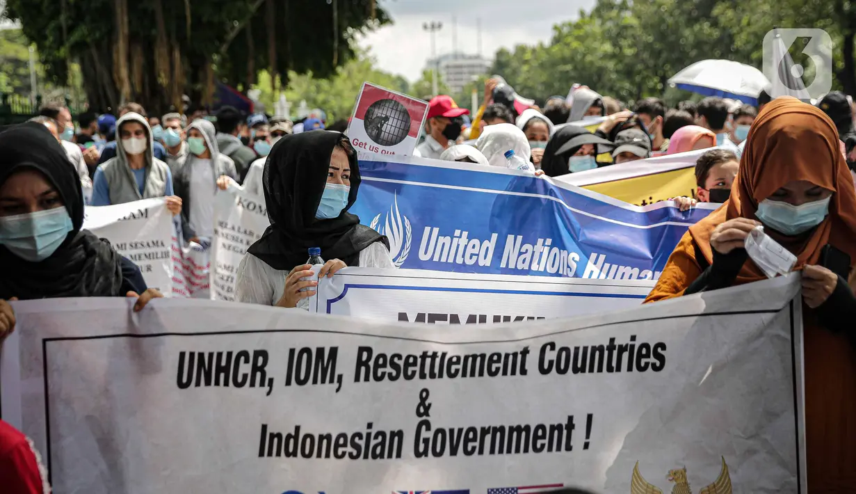 Sejumlah pengungsi Afghanistan membawa spanduk saat berunjuk rasa di kawasan Monas, Jakarta, Rabu (19/1/2022). Mereka menuntut kejelasan untuk berangkat ke negara ketiga setelah lama tinggal di pengungsian. (Liputan6.com/Faizal Fanani)