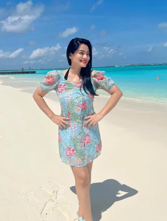 <p>Titi Kamal mengenakan mini dress motif floral berposi di pinggir pantai. (Foto: Instagram titi_kamall)</p>