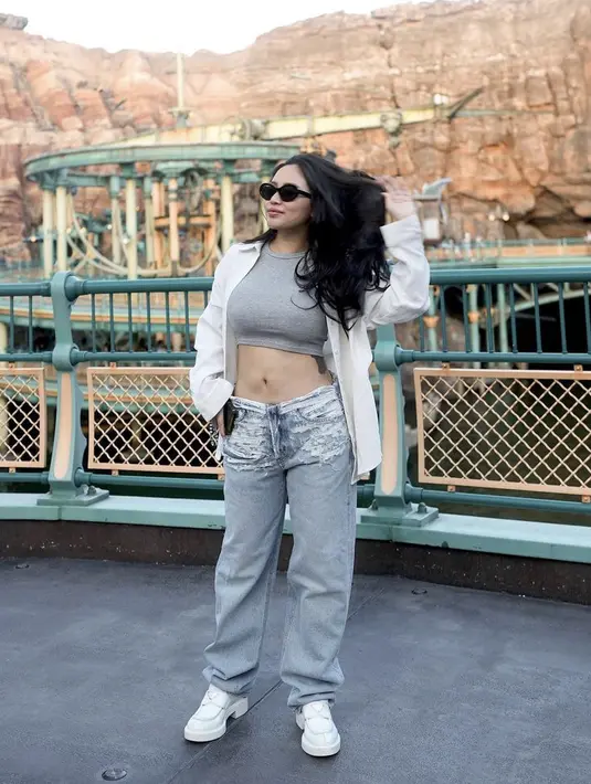 Ibu dua anak ini tampil dengan crop top yang memerlihatkan tatonya dipadukan oversize kemeja putih serta celana denimnya. (@rachelvennya)