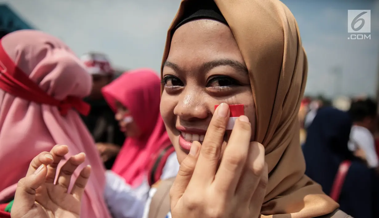 Seorang suporter menempelkan pipinya dengan stiker bendera Merah Putih untuk mendukung Timnas Indonesia U-22 pada laga lanjutan grup B SEA Games 2017 melawan Timor Leste, Minggu (20/8). Indonesia menang 1-0 atas Timor Leste. (Liputan6.com/Faizal Fanani)