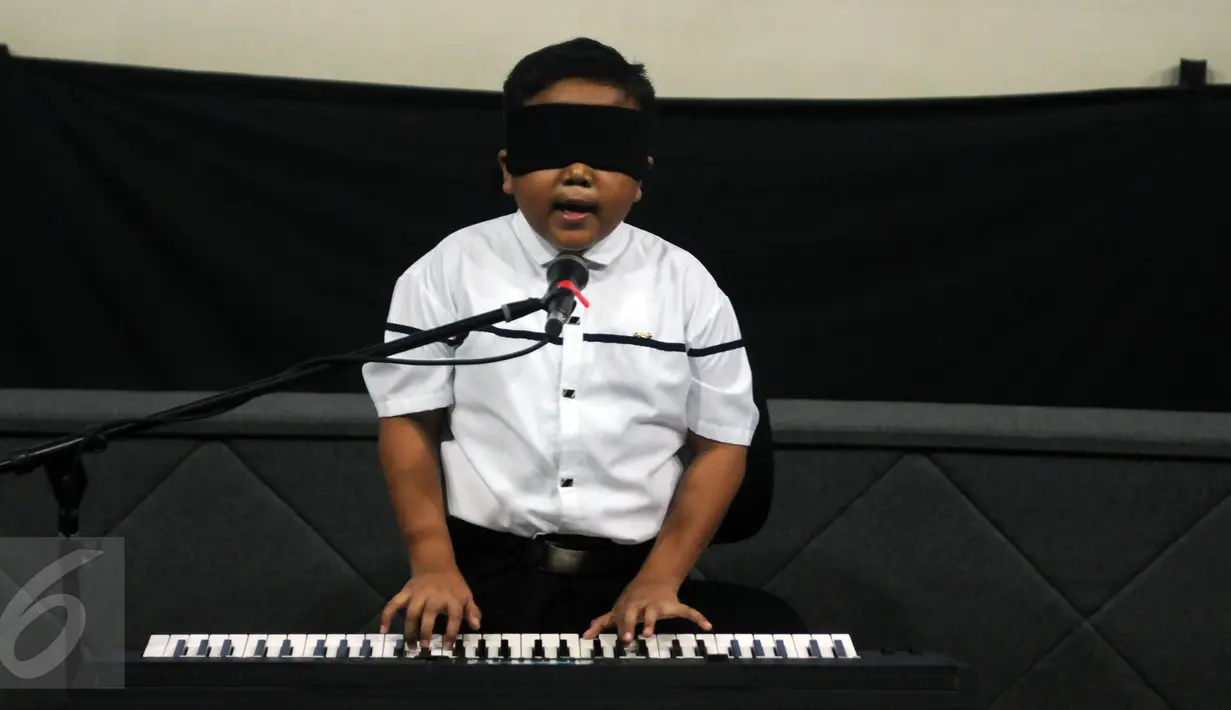 Jefri Setiawan saat bernyanyi sambil memainkan keyboard di Auditorium Kemenpora, Jakarta,  Kamis (14/11). Jefri akan memainkan 50 lagu selama 5 jam nonstop dengan mata tertutup.  (Liputan6.com/Helmi Fithriansyah)