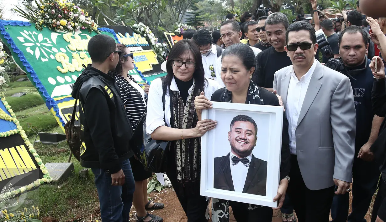 Ibunda Mike Mohede, Amin Yudhayani, memegang foto putranya dalam prosesi pemakaman di TPU Tanah Kusir, Jakarta, Selasa (2/8). Prosesi pemakaman Mike Mohede berjalan diiringi isak tangis keluarga, sahabat dan kekasihnya. (Liputan6.com/Herman Zakharia)