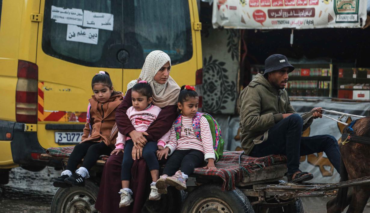 Selain itu, banyak dari sekolah-sekolah yang masih digunakan sebagai tempat penampungan bagi pengungsi. Tampak dalam foto, seorang wanita mengantar anak-anaknya ke sekolah dengan kereta kuda di Deir al-Balah, di Jalur Gaza tengah, pada 10 Desember 2025. (BASHAR TALEB/AFP)