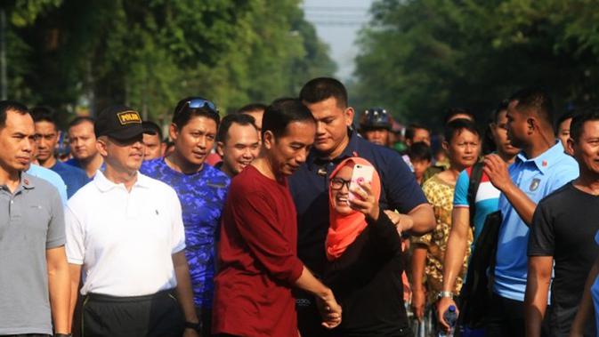 Presiden Joko Widodo atau Jokowi (kaus merah) diajak selfie warga saat berolahraga di Solo CFD, Jalan Slamet Riyadi, Minggu (1/4/2018) pagi. (Antonius Christian/Radar Solo/Jawa Pos Group)