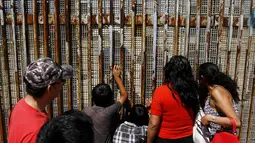 Warga berbincang dengan keluarga mereka di pagar perbatasan antara Meksiko dan Amerika Serikat, Playas Tijuana, Meksiko, (12/4).Hal ini dilakukan karena banyak warga yang tak punya biaya atau visa untuk mengunjungi keluarganya. (REUTERS / Jorge Duenes)