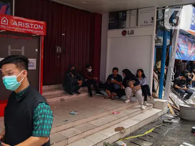 Beberapa orang terlihat duduk di depan sejumlah toko dan perkantoran yang tutup di sekitar kompleks dengan Glodok Plaza, Jakarta, Kamis (16/1/2025). (Liputan6.com/Angga Yuniar)