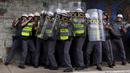 Polisi Anti Huru hara melindungi diri di balik perisai saat diserang para demonstran, Brasil, Jumat (8/1/2016). Pengunjuk rasa protes terhadap kenaikan tarif untuk bus kota di Sao Paulo. (Reuters/Nacho Doce)