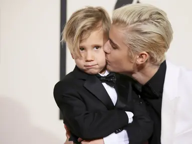 Justin Bieber mencium adiknya, Jaxon, saat berpose di karpet merah Grammy Awards 2016 di Staples Center, Los Angeles, Senin (15/2). Meski terpaut usia 15 tahun, namun pelantun 'What Do You Mean' itu tampak dekat dengan sang adik. (REUTERS/Danny Moloshok)