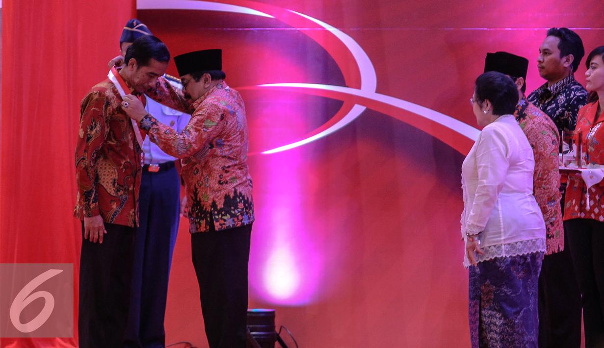 Gubernur Jatim sekaligus Ketum GMNI Soekarwo mengalungkan medali kepada Presiden Jokowi saat menghadiri pembukaan Kongres III Persatuan Alumni GMNI di Hall C-2, Ji-Expo, Kemayoran, Jakarta, Jumat (8/7/2015).  (Liputan6.com/Faizal Fanani)