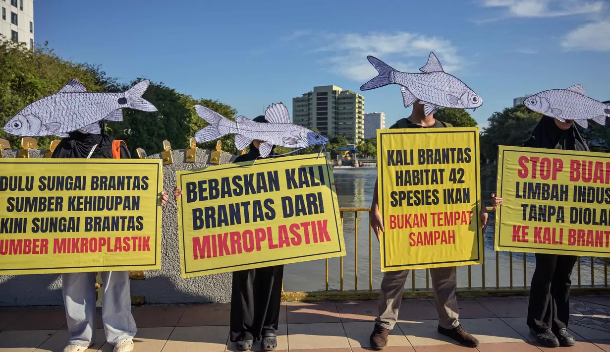 Aktivis dari Ecoton (Pengamatan Ekologi dan Konservasi Lahan Basah) yang mengenakan topeng ikan ikut serta dalam unjuk rasa menyerukan sungai bersih bebas sampah dan limbah industri, serta perlindungan ikan sungai, sebagai bagian dari perayaan Hari Lingkungan Hidup Sedunia di Surabaya, Jawa Timur, Jumat 5 Juni 2026. (JUNI KRISWANTO/AFP)