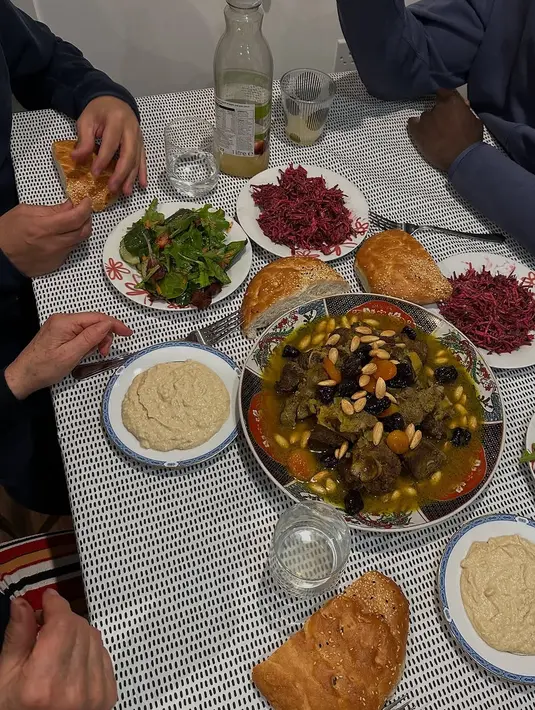 Hannah juga membagikan momen berbuka puasa bersama keluarga dengan hidangan khas yang menggugah selera. Di meja makan, tampak sepiring besar tagine domba dengan kacang almond dan buah kering, roti hangat, salad segar, dan hummus makanan khas Timur Tengah. Ia mengaku meski sulit mengatur jadwal makan di London saat Ramadhan, namun iftar bersama orang-orang tercinta terasa sangat istimewa. (Liputan6.com/IG/@hannahalrashid)