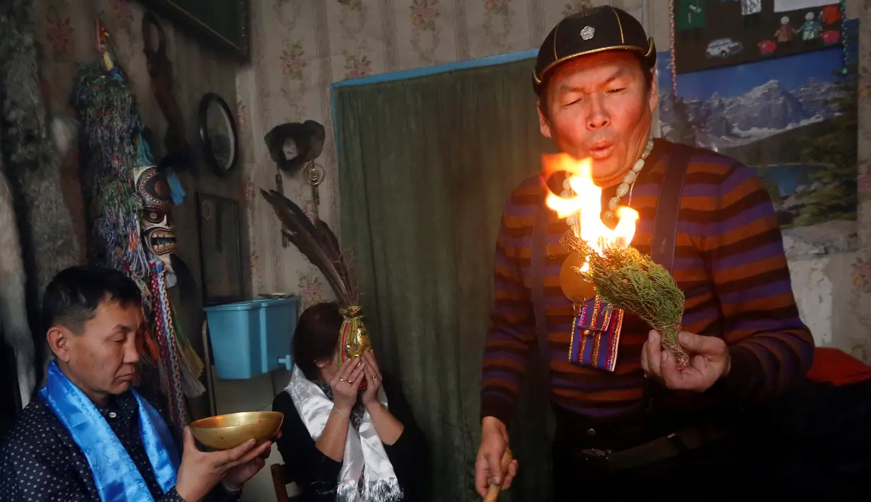 Seorang dukun melakukan ritual bersama dua pelanggan untuk mengusir roh-roh jahat di kediamannya di Kota Kyzyl, Tuva, Siberia, Rusia, (3 /11). (REUTERS/Ilya Naymushin)
