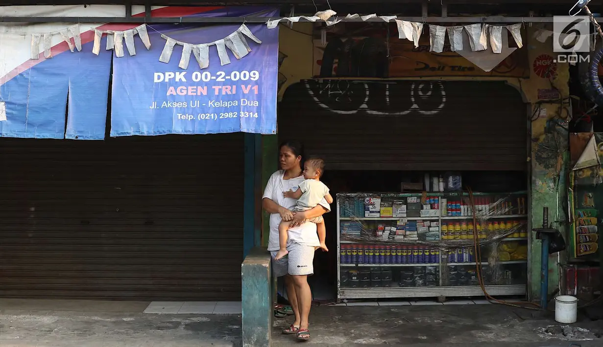 Warga menggendong bayinya di depan bengkel yang tutup usai kerusuhan di Mako Brimob Kelapa Dua, Depok, Jawa Barat, Rabu (9/5). Aparat kepolisian melakukan sterilisasi di kawasan tersebut lebih dari 100 meter. (Liputan6.com/Immanuel Antonius)