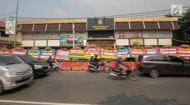 Kendaraan melintas di depan Polres Jakarta Barat yang dipenuhi karangan bunga, Jumat (23/11). Karangan bunga yang dikirimkan warga tersebut diberikan guna mendukung kepolisian dalam memberantas aksi premanisme di Jakbar. (Liputan6.com/Faizal Fanani)