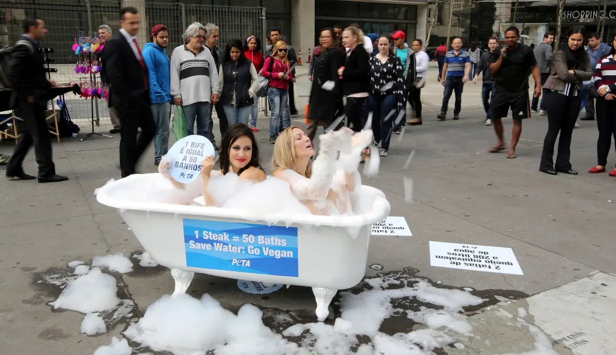 Sejumlah pengguna jalan melihat aksi kampanye aktivis wanita dari PETA yang mandi dengan busa di Jalan Paulista di Sao Paulo, Brasil, Selasa (2/8). Aksi itu untuk mengajak masyarakat beralih ke pola makan vegetarian. (REUTERS/Paulo Whitaker)
