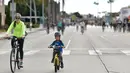 Seorang wanita dan anak kecil mengendarai sepeda di jalan-jalan bebas kendaraan bermotor selama acara CicLAvia di Culver City, Los Angeles, Minggu (3/3). Di Los Angeles, car free day disebut juga CicLAvia. (Chris Delmas/AFP)