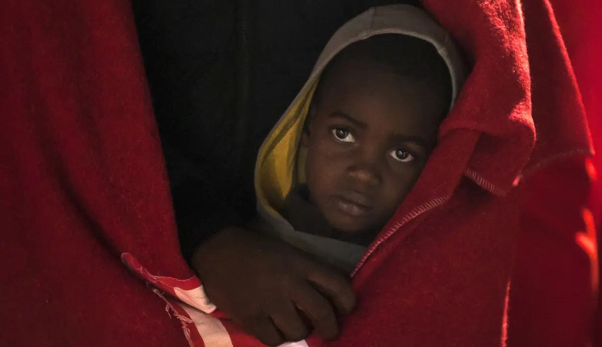 Seorang anak imigran berdiri di kapal penyelamat ketika tiba di pelabuhan Malaga, Spanyol, Selasa, (11/2/2020). Otoritas maritim Spanyol pada Senin (11/2) menyelamatkan 119 imigran dari laut dan sedang mencari 67 lainnya yang mencoba mencapai pantai Eropa. (AP Photo/Jesus Merida)