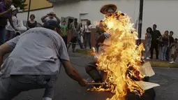 Patung bergambar Presiden Venezuela Nicolas Maduro dibakar oleh warga di Caracas , Venezuela, (27/3). Proses ini juga masuk dalam tradisi " Pembakaran Yudas " tetapi bedanya patung tersebut ditempel gambar Nicolas Maduro. (REUTERS / Marco Bello)