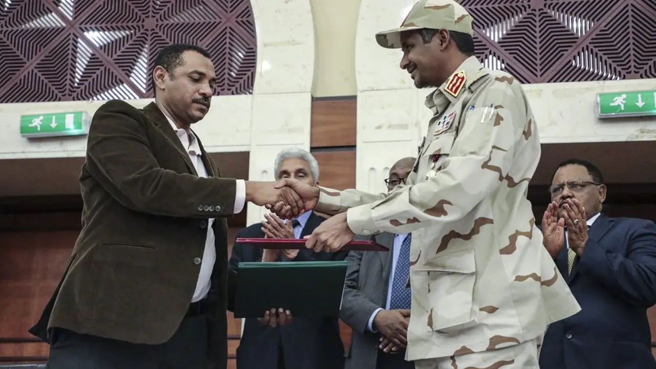 Jenderal Mohammed Hamdan Dagalo, kanan, dan pemimpin gerakan pro-demokrasi Sudan Ahmad al-Rabiah berjabat tangan setelah menandatangani dokumen pembagian kekuasaan di Khartoum, Sudan, Rabu, 17 Juli 2019.