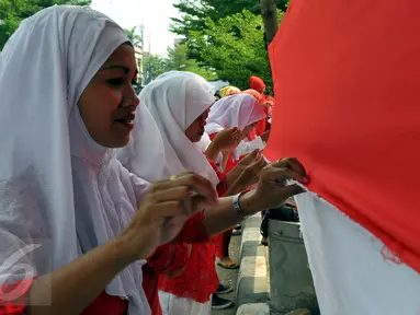 Sejumlah warga saat mengikuti lomba menjahit bendera Merah Putih sepanjang 500 meter di Kelurahan Pekojan, Jakarta, Minggu (16/8/2015). Lomba yg di ikuti oleh 12 RW dan 144 RT ini mengirimkan lima orang dlm setiap Rtnya. (Liputan6.com/Panji Diksana)