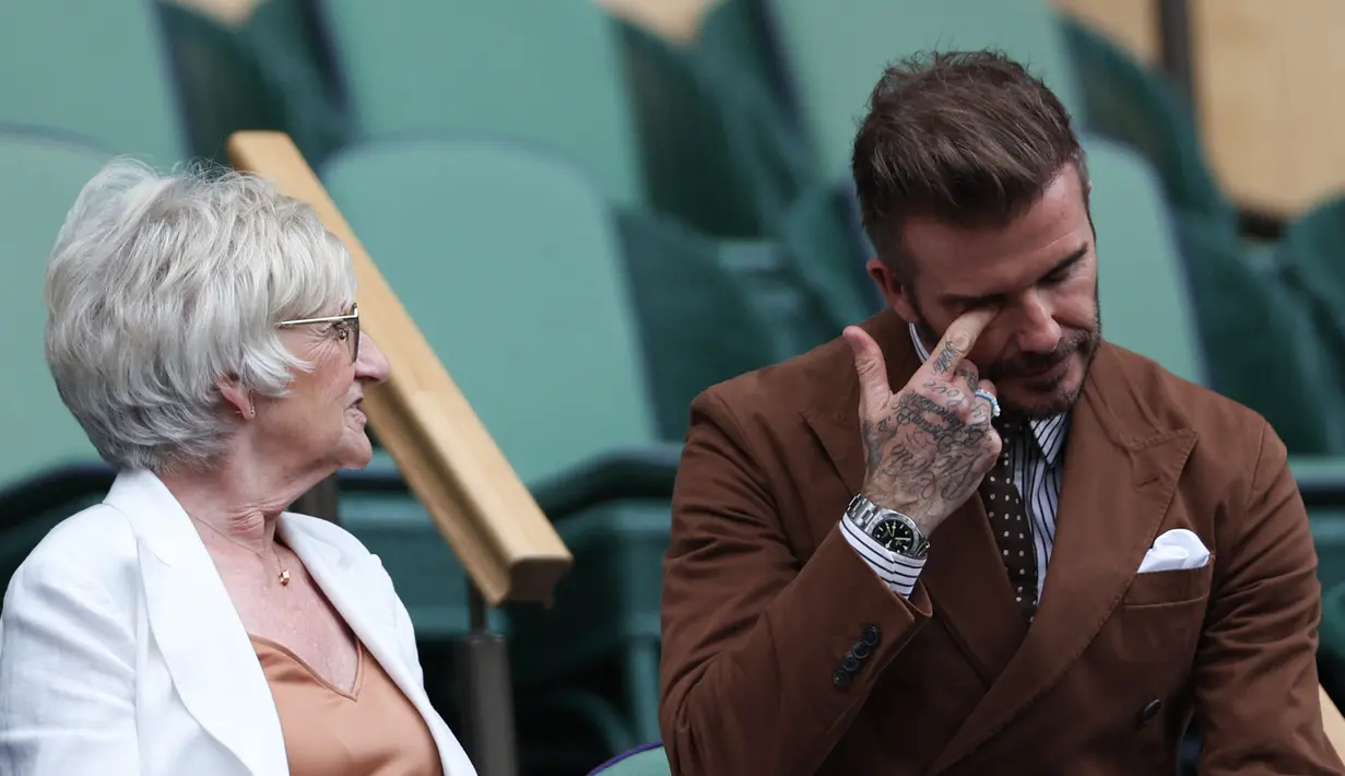 <p>Mantan pesepakbola David Beckham dan ibunya Sandra Georgina West bereaksi dari Royal Box di Centre Court selama pertandingan tenis perempat final tunggal putri antara Simona Halep dari Rumania dan pemain AS Amanda Anisimova pada hari kesepuluh Kejuaraan Wimbledon 2022 di The Klub Tenis All England di Wimbledon, London (6/7/2022). (AFP/Adrian Dennis)</p>