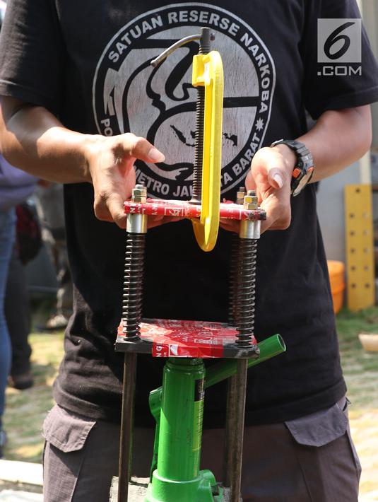 Petugas mengangkut barang bukti alat pencetak pil ekstasi di sebuah perumahan di Kawasan Pondok Rajeg, Cibinong, Jawa Barat, Senin (24/9). Polisi juga menahan tiga tersangka dan sejumlah barang bukti terkait. (Liputan6.com/Helmi Fithriansyah)