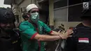 Artis Claudio Martinez memakai masker dengan tangan di borgol usai rilis narkoba di Polres Jakarta Barat, Jumat (9/11). Claudio ditangkap dengan barang bukti 7,96 gram ganja. (Liputan6.com/Faizal Fanani)