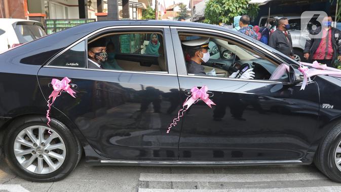 Pengantin menggunakan mobil dinas Pemkot Bekasi menuju lokasi pernikahan di Bekasi, Jawa Barat, Sabtu (12/9/2020). Wakil Wali Kota Bekasi menyediakan fasilitas gratis mobil dinas pada hari Sabtu dan Minggu untuk antar jemput pengantin saat pandemi COVID-19. (Liputan6.com/Herman Zakharia)