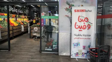 Spanduk yang mengidentifikasi produk lokal dipajang di pintu masuk sebuah supermarket di Ramallah di Tepi Barat yang diduduki, sebagai bagian dari kampanye yang lebih luas yang mendesak warga Palestina untuk memboikot produk Israel dan membeli barang-barang buatan lokal, Selasa (26/12/2023). (Jaafar ASHTIYEH / AFP)