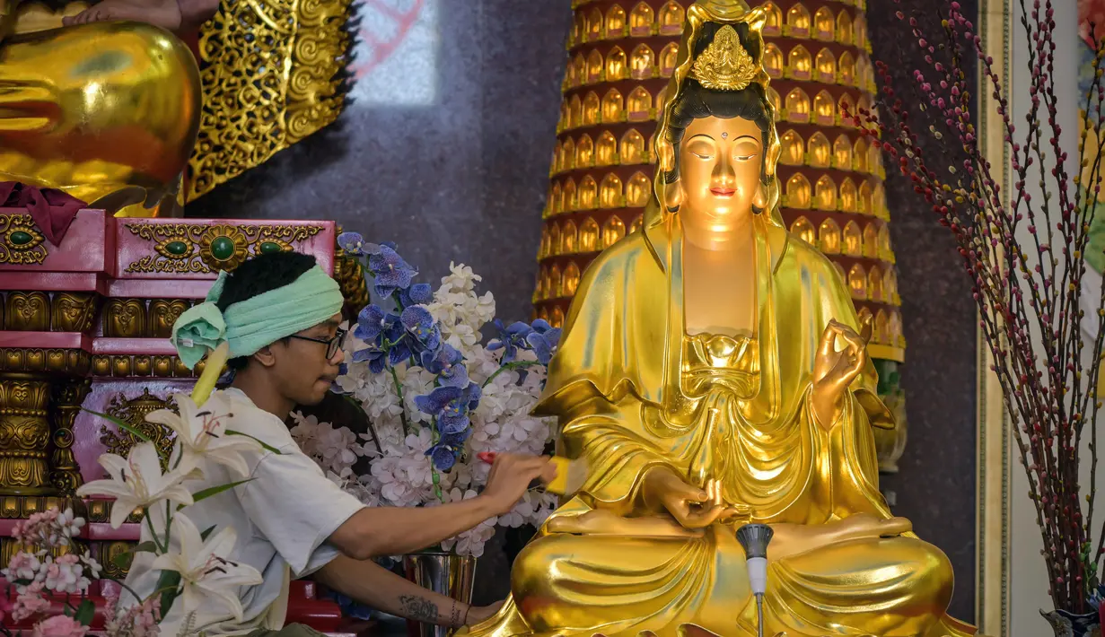 Dalam prosesinya, patung dibersihkan menggunakan air yang telah dicampur dengan berbagai jenis bunga, seperti sedap malam, mawar, dan melati. Tampak dalam foto, seorang pria membersihkan patung Buddha sebagai persiapan perayaan Tahun Baru Imlek 2577 Kongzili di Vihara Buddhayana, Surabaya, Jawa Timur pada Senin 9 Februari 2026. (JUNI KRISWANTO/AFP)