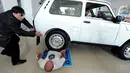 Seorang pengendara mobil melindas tubuh Norik Yajian pada sebuah atraksi di Tbilisi, Georgia, Selasa (16/2). Atraksi ini nekat dilakukan Norik untuk memecahkan rekor Guinness. (AFP PHOTO/Vano SHLAMOV)