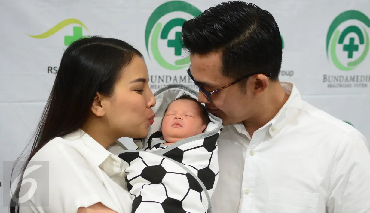 Pemain Sinetron Tya Ariestya dan suaminya Irfan mencium anak pertamanya di rumah sakit kasawan Cikini, Jakarta, Sabtu (6/8/2016). Anak pertama pasangan Tya dan Irfan diberi nama Muhammad Irfan Ratinggang.( Liputan6.com/Herman Zakharia)