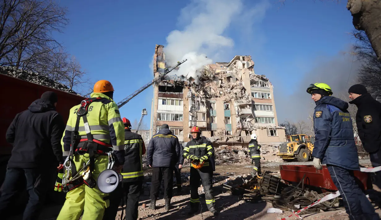 Satu gedung terbakar, sementara lantai atas bangunan lainnya hancur total. Tampak dalam foto, petugas penyelamat memadamkan kebakaran di sebuah gedung perumahan yang rusak akibat serangan Rusia di Ternopil, Ukraina, pada Rabu 19 November 2025. (AP Photo/Rostyslav Kovalchuk)