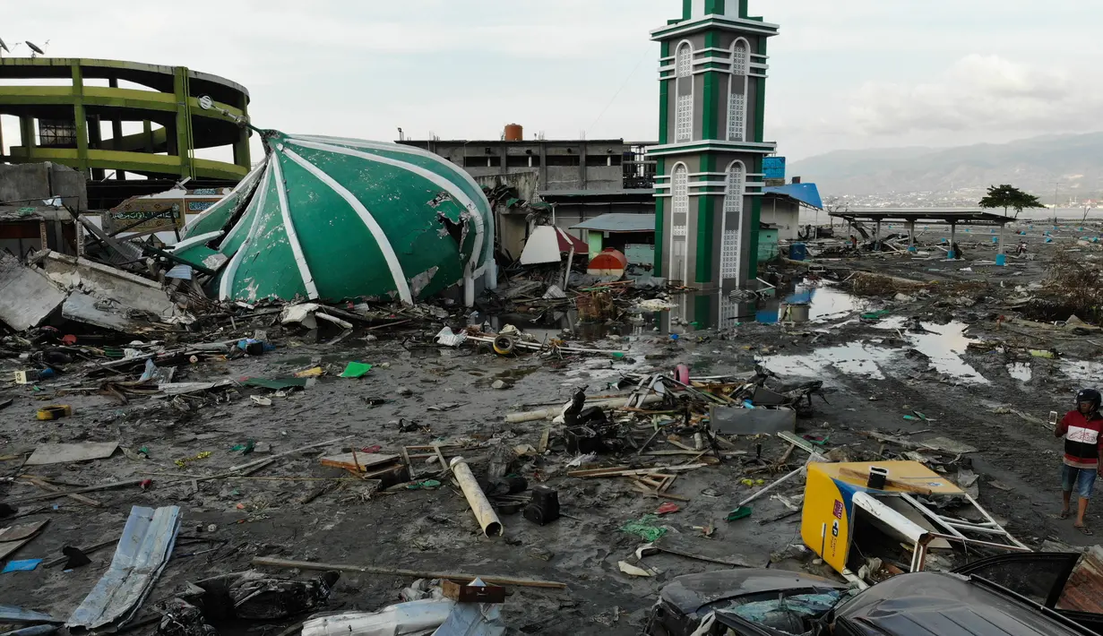 Seorang pria melewati kubah Masjid Raya Baiturrahman yang runtuh setelah gempa bumi dan tsunami menghantam Palu di Sulawesi Tengah, Rabu (3/10). Kubah dan beberapa dinding masjid roboh akibat guncangan gempa dahsyat. (AFP PHOTO / JEWEL SAMAD)