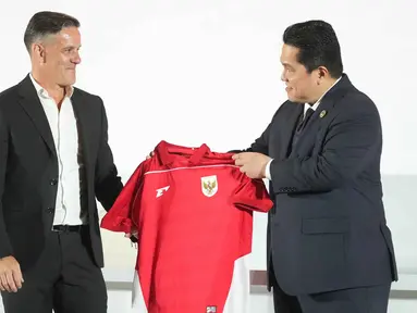Ketua Persatuan Sepak Bola Seluruh Indonesia (PSSI), Erick Thohir (kanan) menyerahkan jersey tim kepada pelatih kepala tim nasional Indonesia yang baru ditunjuk, John Herdman, saat konferensi pers di Jakarta, Selasa 13 Januari 2026. Persatuan Sepak Bola Seluruh Indonesia (PSSI) resmi memperkenalkan John Herdman sebagai pelatih baru Timnas Indonesia. (AP Photo/Achmad Ibrahim)