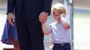 Pangeran George mengusap matanya sambil menggenggam tangan sang ayah, Pangeran William setibanya di Bandara Tegel, Berlin, Rabu (19/7). George ikut dalam tur keluarga kerajaan Inggris bersama Pangeran William dan Kate Middleton. (Kay Nietfeld/dpa via AP)