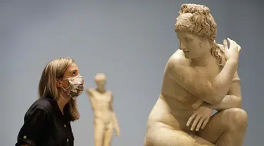 Seorang pegawai museum melihat ke arah patung marmer Crouching Venus, Romawi, abad ke-2 M, saat jumpa pers di The British Museum di London, Senin, (24/8/2020). Rute satu arah baru mengitari galeri Lantai Dasar akan memungkinkan pengunjung mengakses ribuan objek. (AP Photo/Kirsty Wigglesworth)