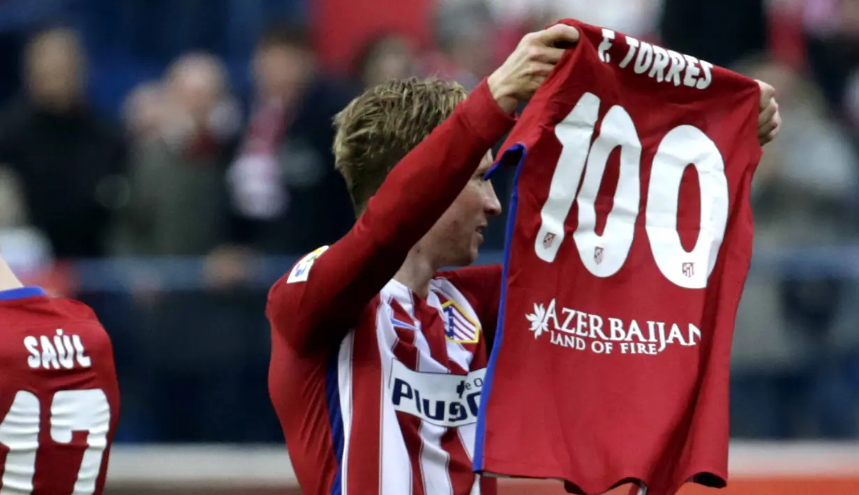 Pemain Atletico Madrid, Fernando Torres mengangkat baju bertuliskan 100 gol yang telah dicetaknya bersama Atletico Madrid pada Lanjutan La Liga Spanyol di Stadion Vicente Calderon, Sabtu (6/2/2016).  (EPA/Javier Lizon)