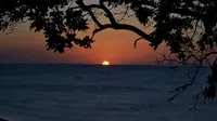 Matahari mulai tenggelam terselubung air laut di Pantai Batu Kepala. (Liputan6.com/Ola Keda)