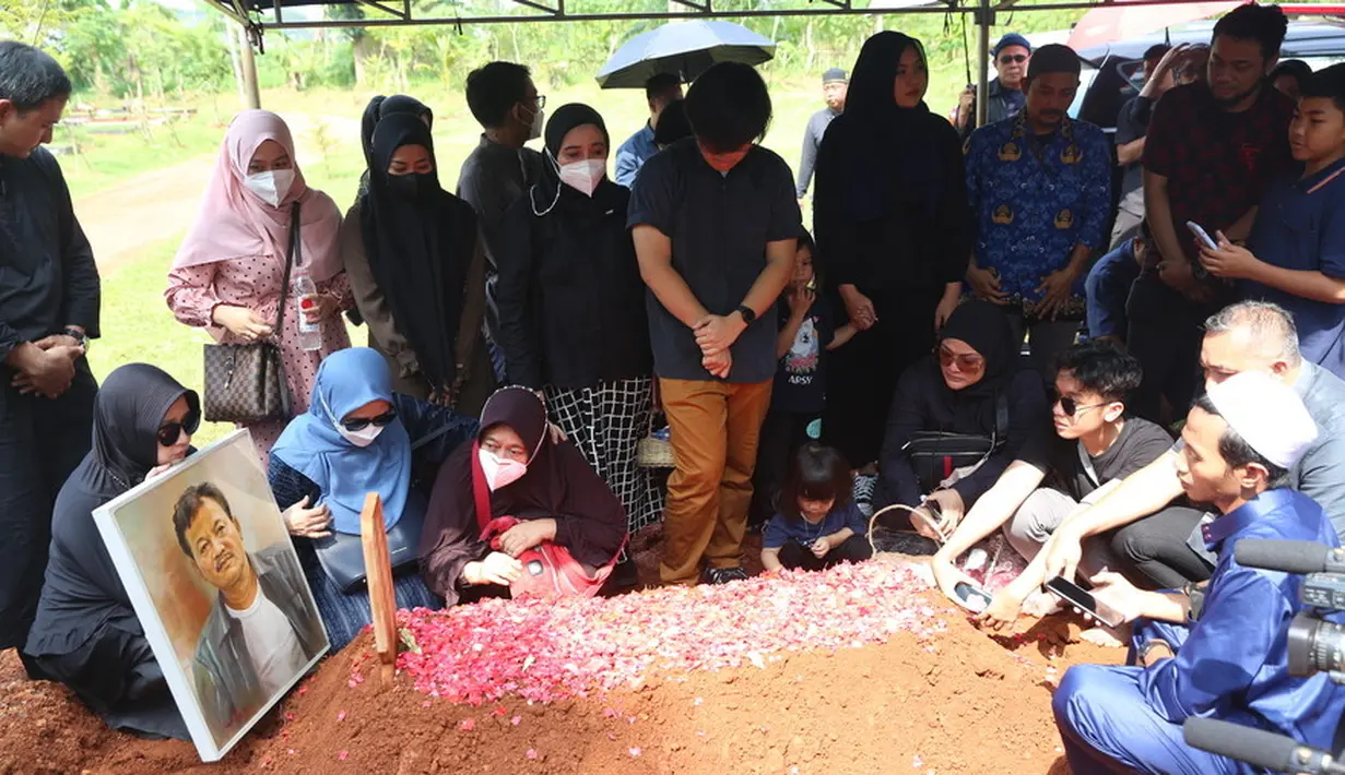 Setelah peti jenazah tertutup tanah merah, istri Eeng Saptahadi dan anak serta kerabat langsung menaburkan bunga di makam Eeng. Selain terpapar covid-19, Eeng juga sudah dipasang alat bantu pernapasan sebelum menghembuskan napas terakhirnya. [Foto: Budy Santoso/KapanLagi.com]