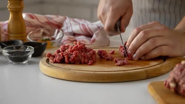 Seorang perempuan sedang menghaluskan daging menggunakan pisau (Foto Dok: Freepik/freepik)