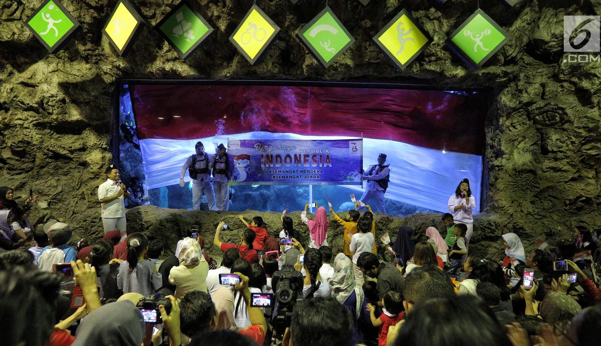 Penyelam membentangkan spanduk saat pengibaran bendera Merah Putih untuk memperingati HUT Ke-73 RI di SeaWorld Ancol, Jakarta, Jumat (17/8). Pengibaran bendera melibatkan para penyelam profesional dan artis peran Marsha Aruan. (Liputan6.com/Faizal Fanani)