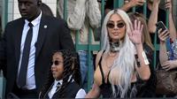 Kim Kardashian dan North West melambai ke arah kamera saat menghadiri peragaan busana Jean-Paul Gaultier di sela Paris Fashion Week Fall/Winter 2023. (dok. AFP)
