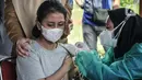 Petugas kesehatan mendampingi seorang anak saat vaksinasi Covid-19 di RPTRA Pulo Besar, Sunter Jaya, Jakarta Utara, Senin (12/7/2021). Saat ini sebanyak 153.000 anak berusia 12-17 tahun telah divaksinasi dari alokasi 20 juta dosis vaksin Covid-19. (merdeka.com/Iqbal S Nugroho)