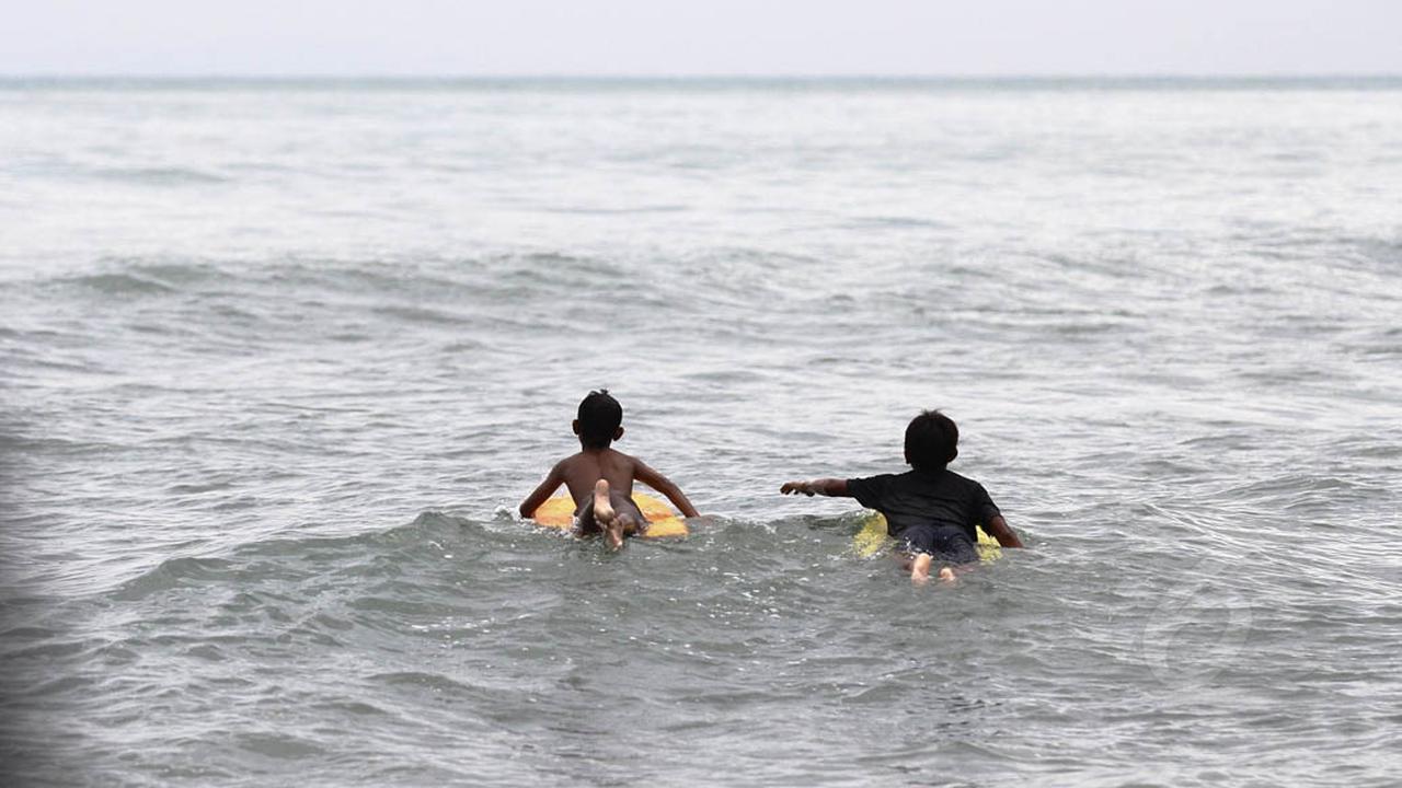 Anak Nelayan Berselancar di Pantai Karang Bolong