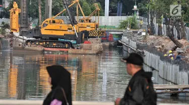 Warga berjalan melintasi turap di Kali Ciliwung Lama, Jakarta, Kamis (11/10). Petugas Dinas Sumber Daya Air Pemprov DKI Jakarta melibatkan alat berat dalam pembangunan turap. (Merdeka.com/Iqbal Nugroho)