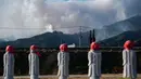 Cuaca kering memicu api cepat meluas, merusak beberapa bangunan dan menimbulkan perintah evakuasi bagi lebih dari 3.000 penduduk. Tampak dalam foto, patung-patung terlihat di sebuah taman sementara asap dari kebakaran hutan mengepul di latar belakang dekat kota Otsuchi, Prefektur Iwate, Jepang pada Sabtu 25 April 2026. (ANDREW CABALLERO-REYNOLDS/AFP)