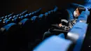 Seorang penonton menunggu dimulainya sebuah film di teater dengan hanya segelintir orang, di bioskop Cineteca Nacional di Mexico City, Rabu (12/8/2020). Setelah ditutup hampir lima bulan akibat Corona, bioskop di ibu kota Meksiko dibuka kembali dengan kapasitas 30%. (AP Photo/Rebecca Blackwell)