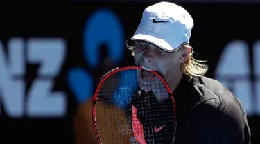 Petenis Kanada Denis Shapovalov menggigit raketnya dengan frustrasi saat pertandingan putaran kedua melawan petenis Prancis Jo-Wilfried Tsonga di kejuaraan tenis Australia Terbuka di Melbourne, Australia, (17/1). (AP Photo / Dita Alangkara)